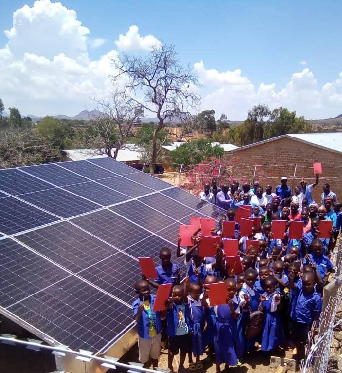 Pupils beside the ground-mounted solar array at their school near Mzuzu